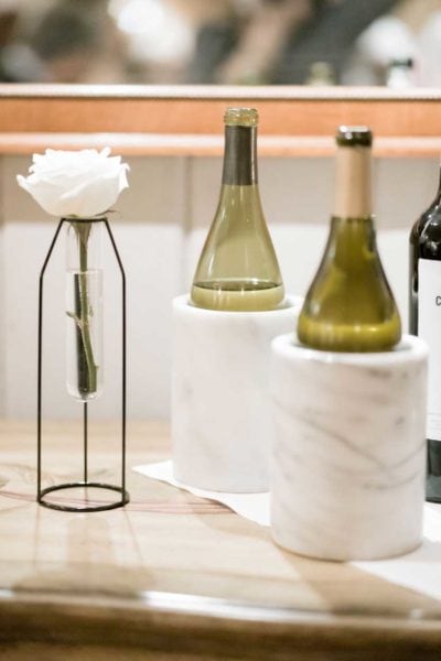 two bottles of wine in wine chillers on a table with a flower in a vase